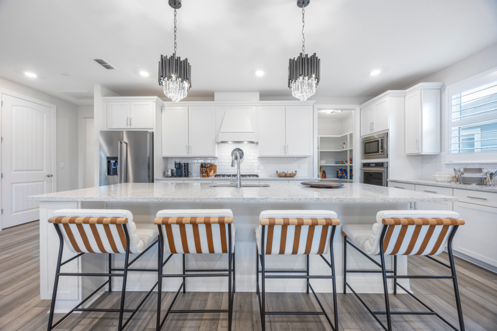 Kitchen at 94 Hickory Pine Drive St. Augustine with large granite island, white cabinets, gas range and pendant lighting