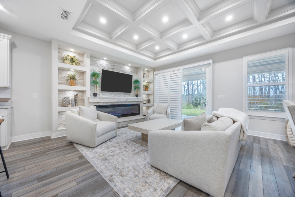 Open living room with coffered ceiling, built-in electric fireplace and sliding doors to lanai at 94 Hickory Pine Drive