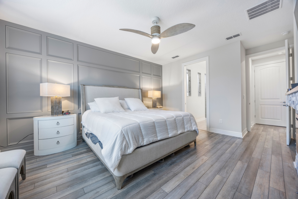 Primary bedroom with paneled accent wall and wood-look flooring at 94 Hickory Pine Drive Summer Bay